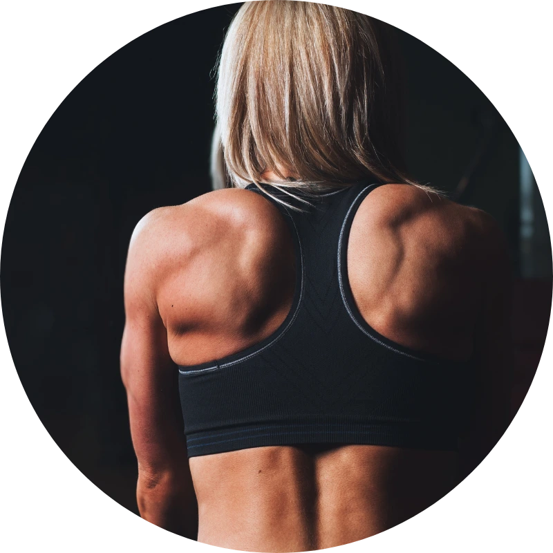 Durchtrainierter Rücken einer Sportlerin in schwarzem Sport-BH im Fitnessstudio.