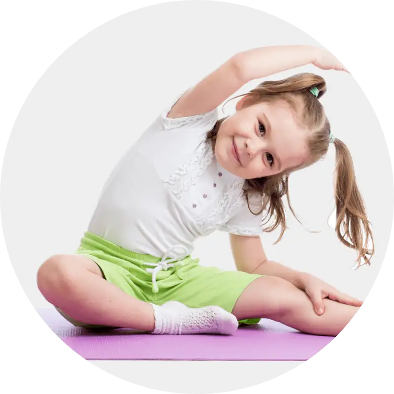 Lächelndes Mädchen in Sportkleidung macht spielerische Dehnübung auf Matte.