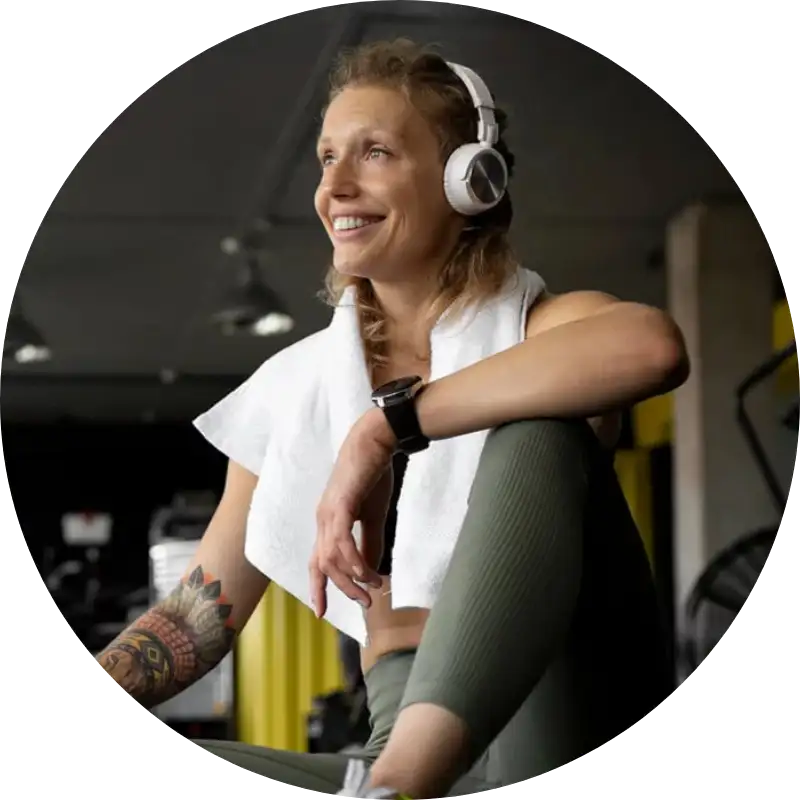 Sportlerin mit Kopfhörern und Handtuch lächelt nach dem Training.